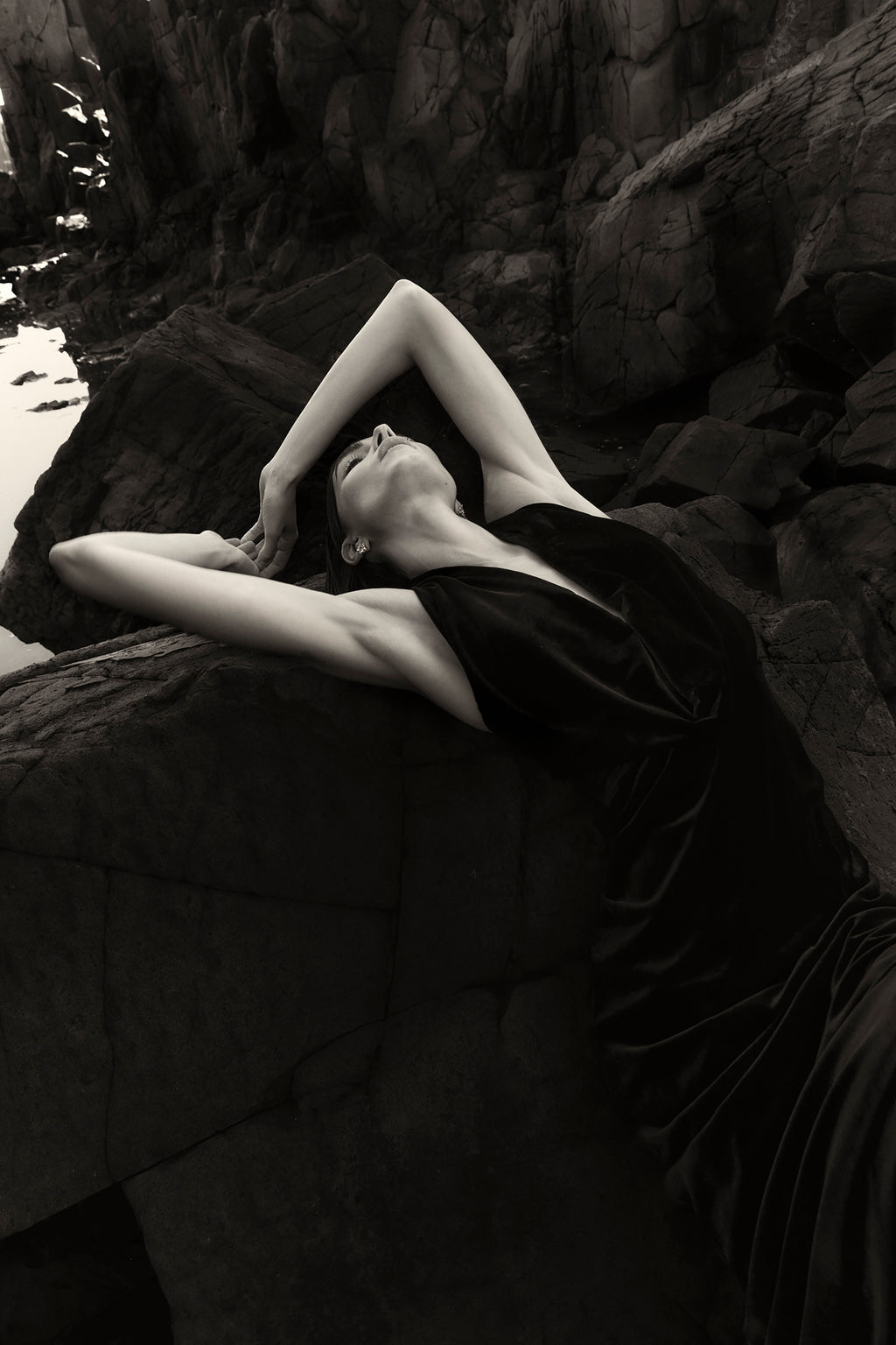 On location image of model wearing Rachel Gilbert Martin Plunge Gown, black velvet halter gown with deep plunge neckline and internal corset.