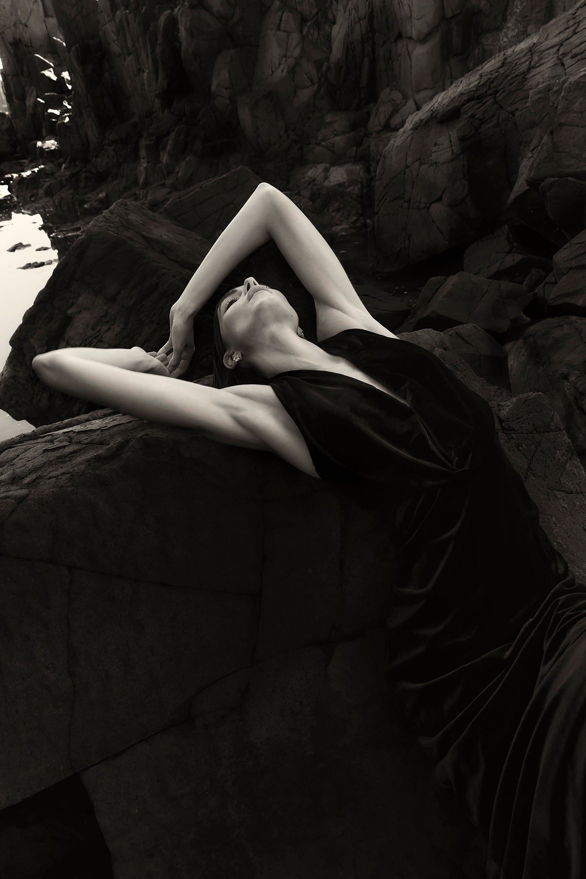 On location image of model wearing Rachel Gilbert Martin Plunge Gown, black velvet halter gown with deep plunge neckline and internal corset.